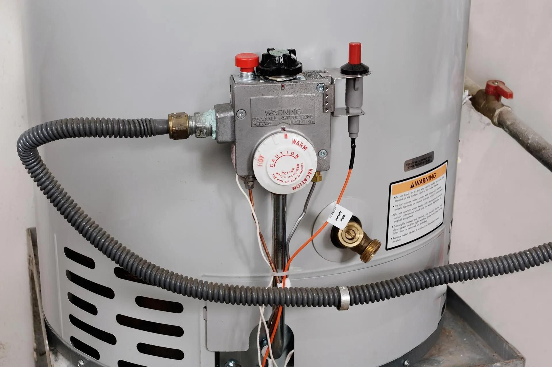 Gas water heater with control panel and gas lines.