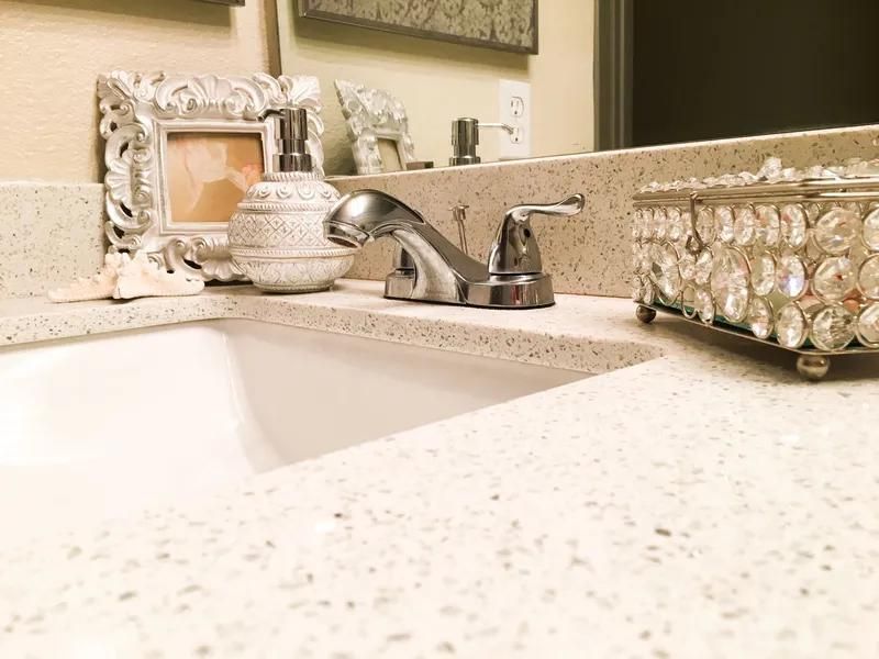 Bathroom sink with chrome faucet, soap dispenser, photo frame, and decorative box.