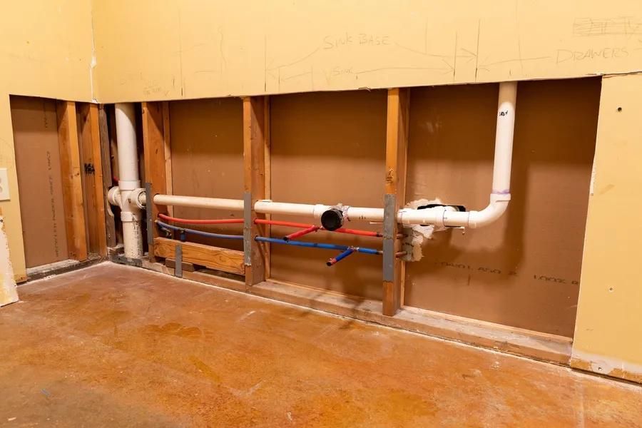 Plumbing pipes inside a wall, including drain, water, and vent lines, during construction or renovation.
