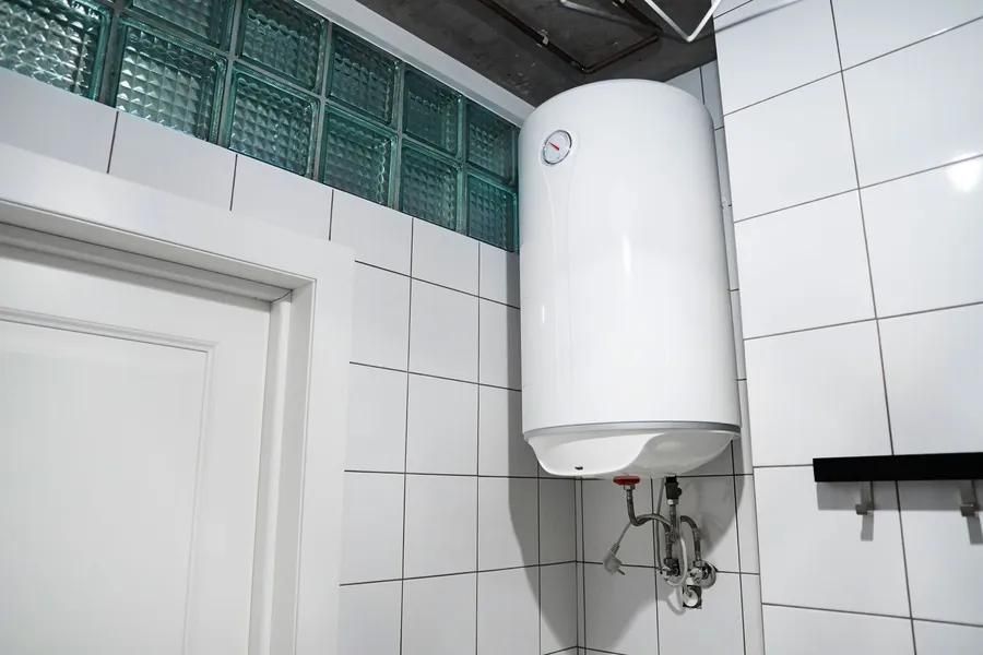 White water heater mounted on tiled bathroom wall.