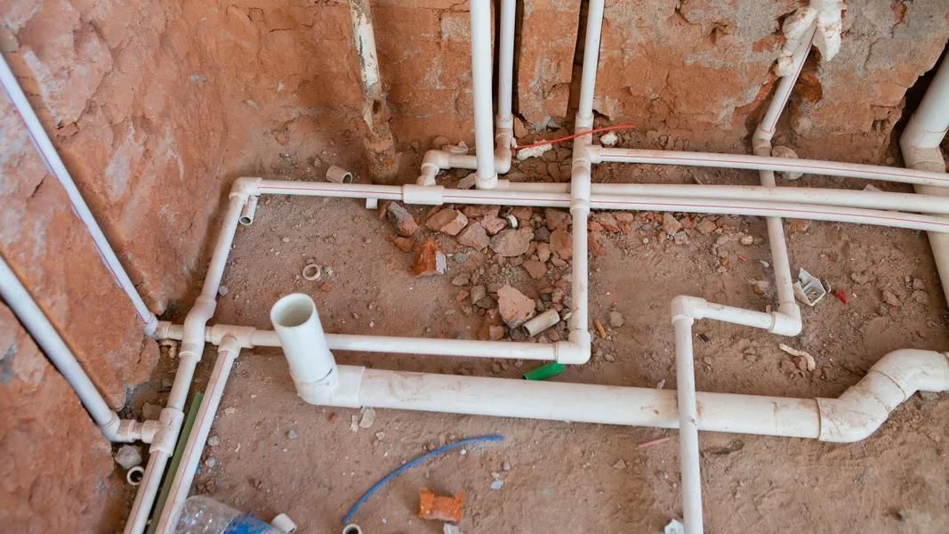 White PVC pipes in a rough wall, likely for plumbing during construction.