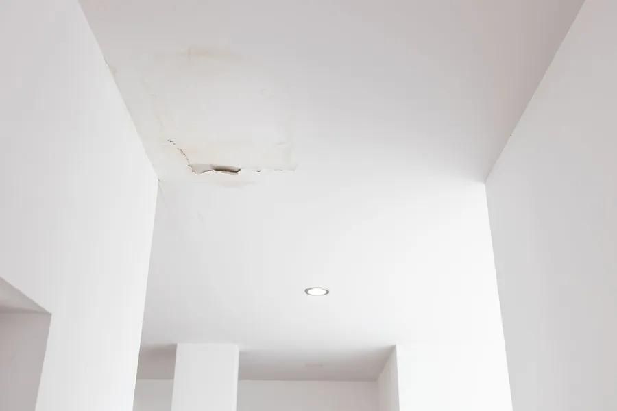White ceiling with water damage, discoloration, and a crack.