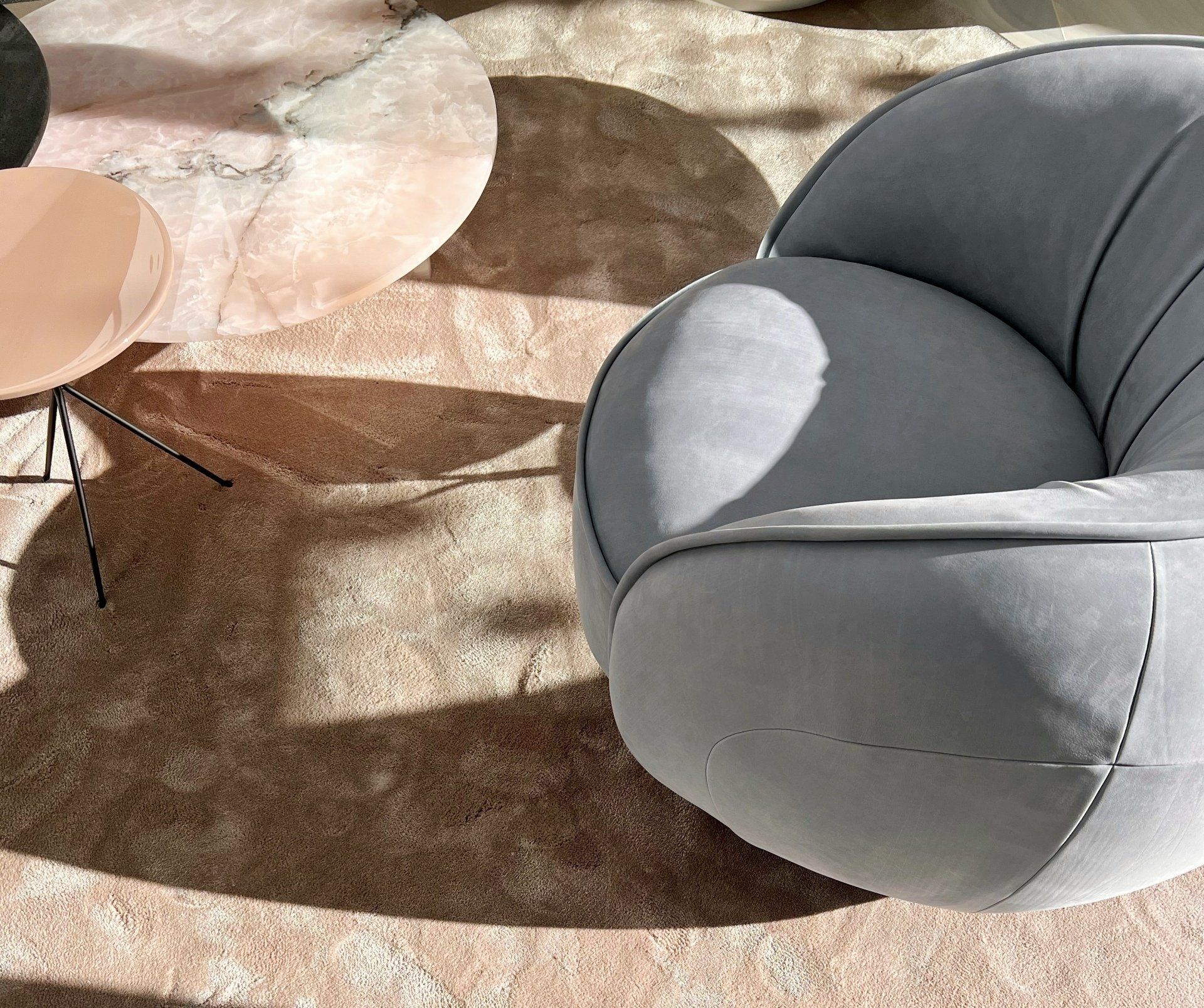 Gray armchair casting shadow on pink and tan rug near a pink side table by Baxter