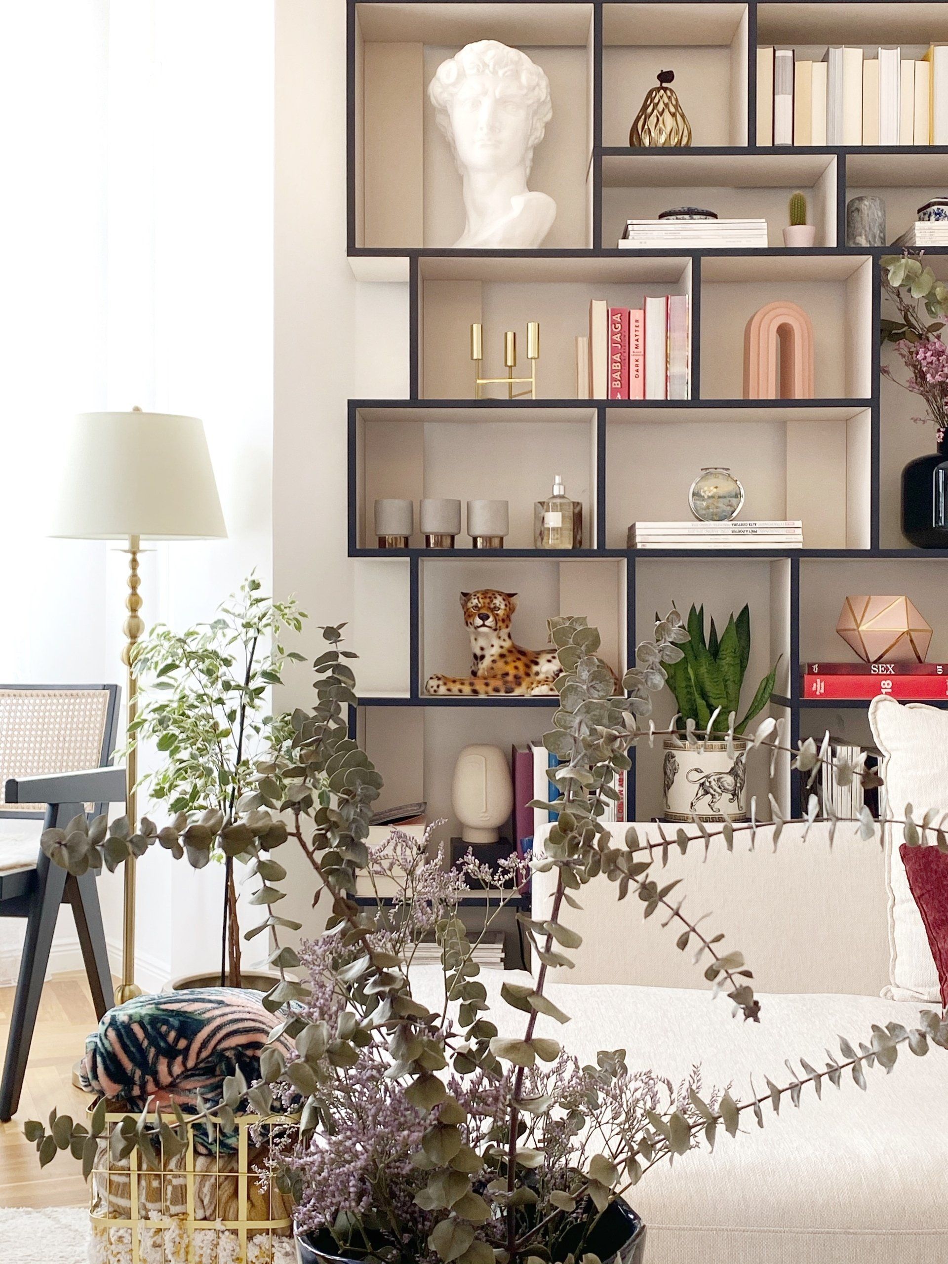 Living room with a modern bookshelf, lamp, plants, and decorative items.