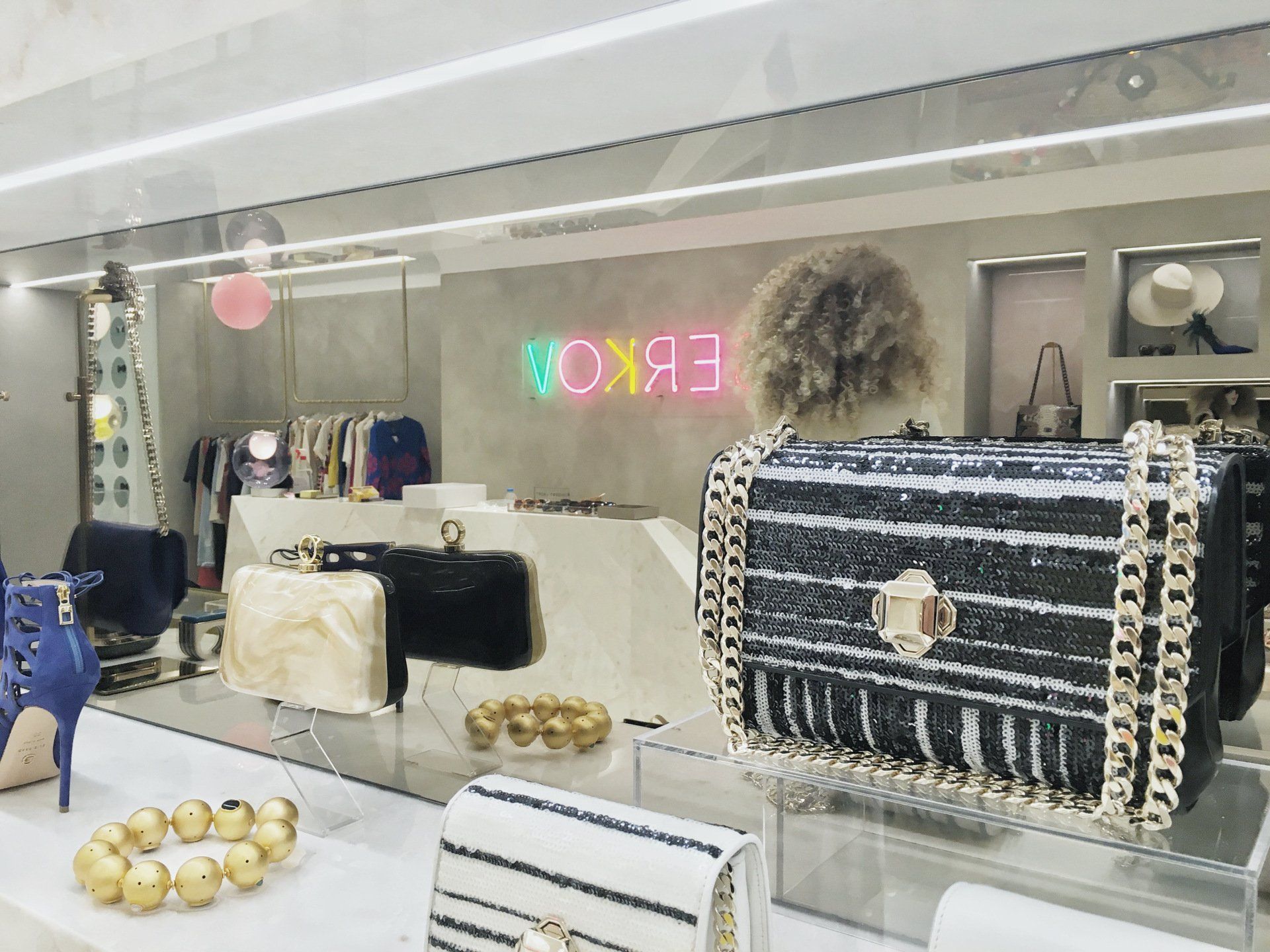Fashion boutique interior: handbags, jewelry, and clothes displayed with neon 