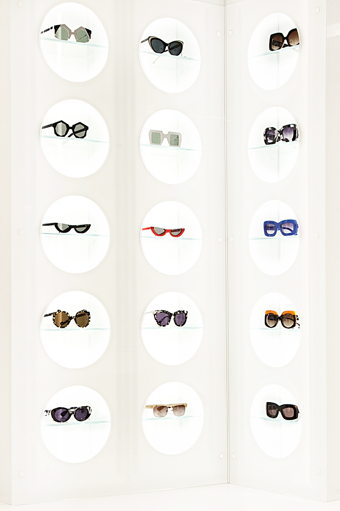 Sunglasses on display in a store window, arranged in rows within white circles.