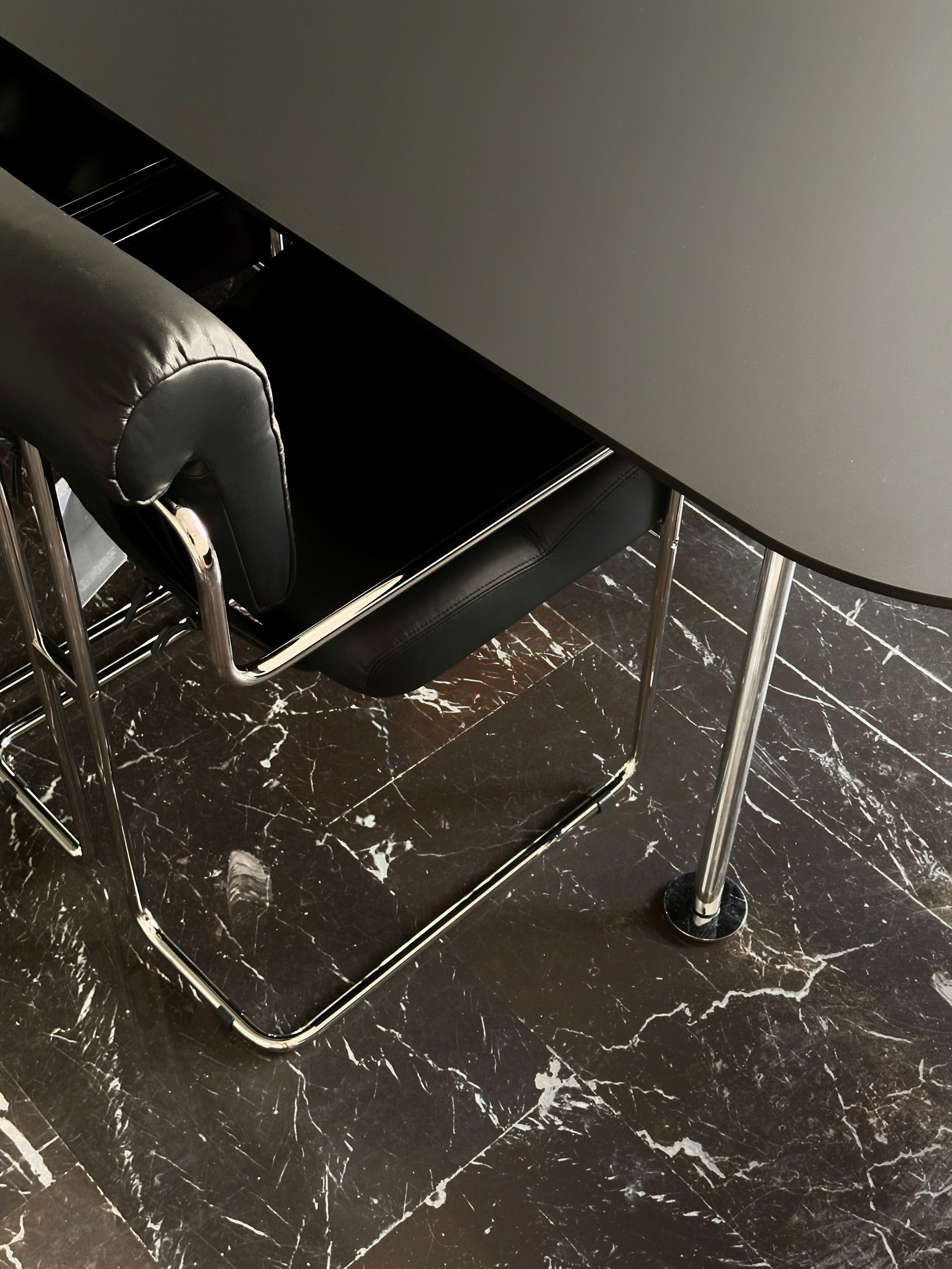 Black table and chair on dark nero marquina marble floor.