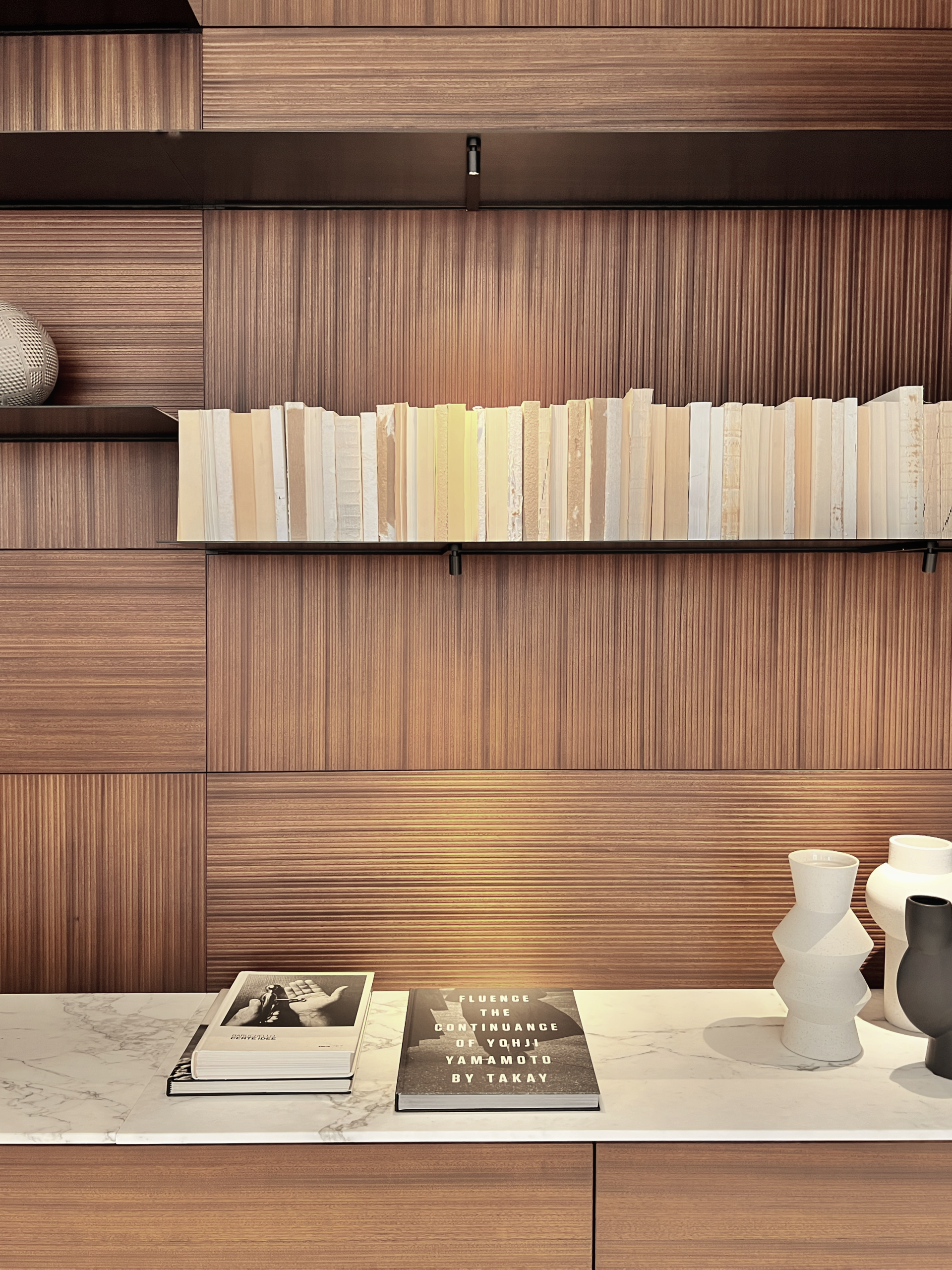 Wooden bookshelf with books, vases, and literature on a countertop.