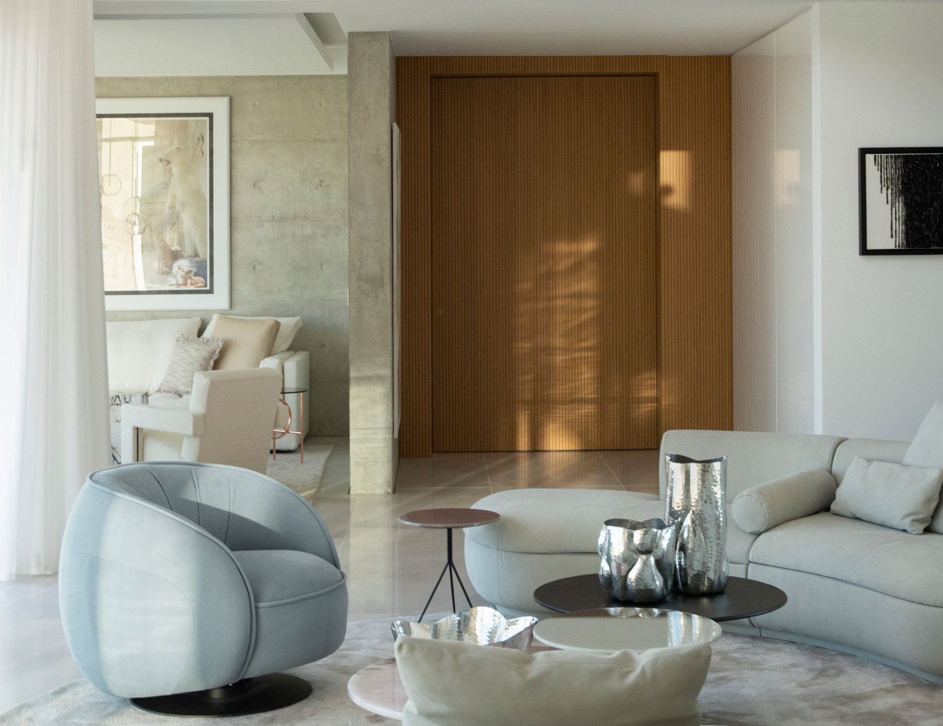 Modern living room with light blue swivel chair, sofa, and brown wood door.