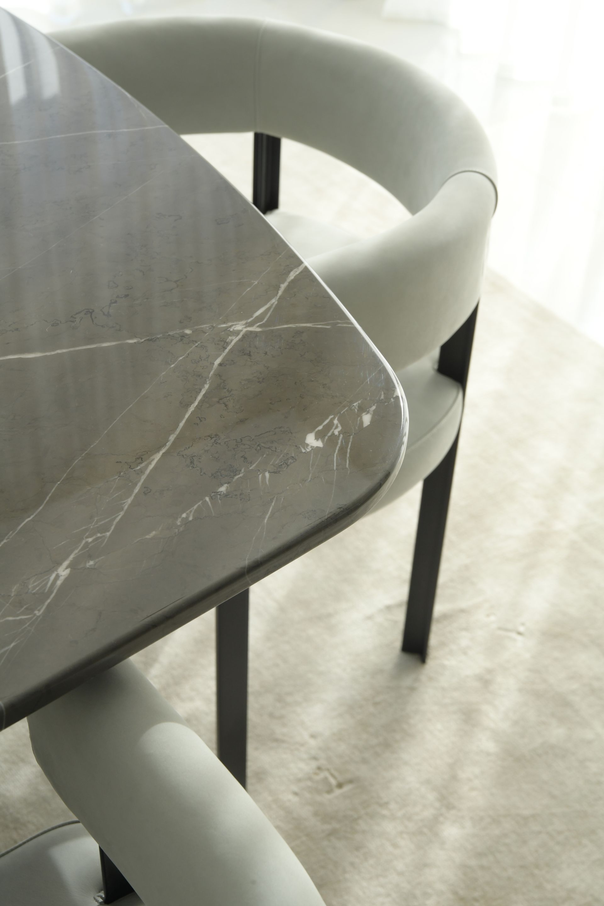 Close-up of a modern dining table with a gray marble top and matching chairs with rounded backs.