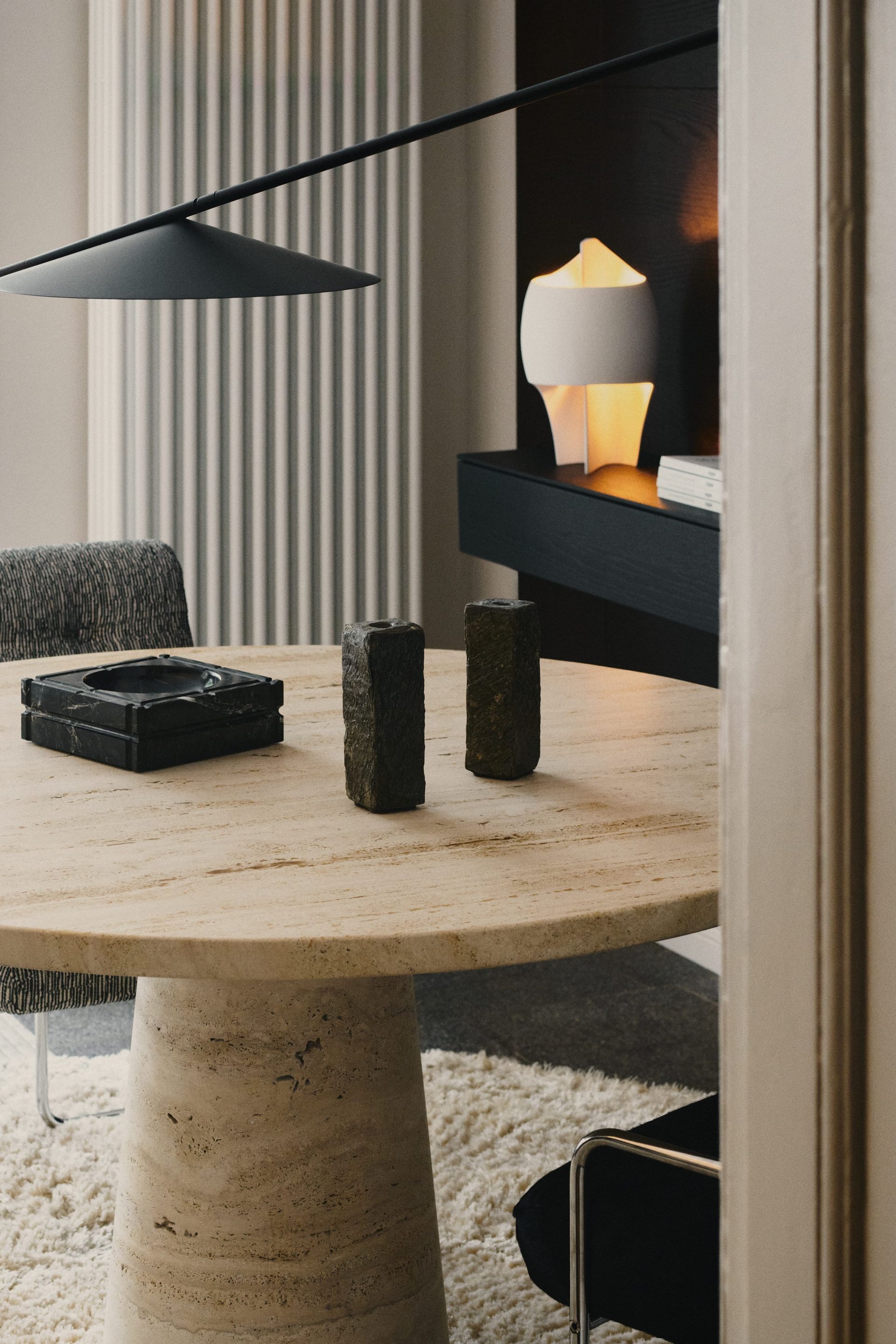 Round stone table with decor, black overhead lamp, and modern side table from demartistudio in Berlin