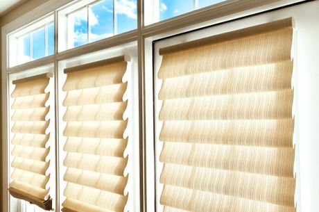 A window with roman shades on it and a blue sky in the background.