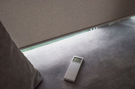 A remote control is sitting on the floor next to a blind.