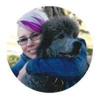 Woman with purple-streaked hair embraces a gray poodle; outdoors.