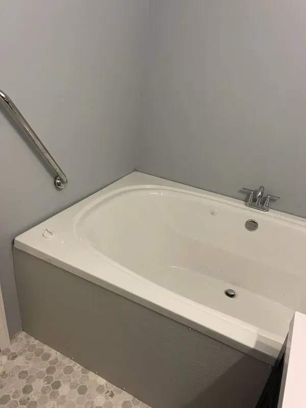 A bathtub with a handle on the side of it in a bathroom.