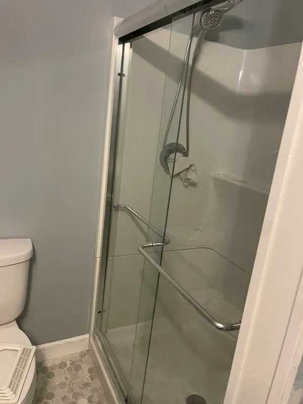 A bathroom with a toilet and a shower with a sliding glass door.