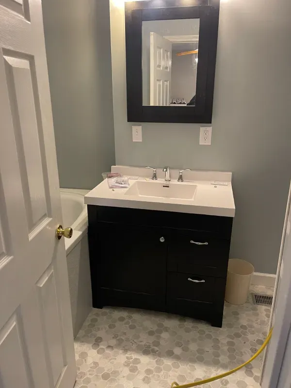 A bathroom with a sink , mirror and bathtub.
