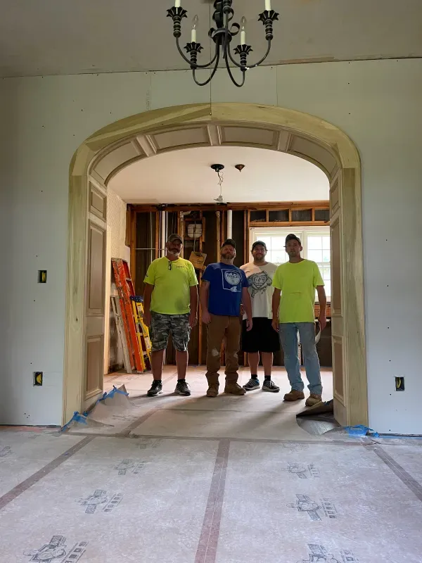 A group of men standing in a room with a chandelier hanging from the ceiling