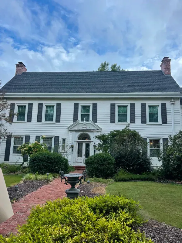 A large white house with black shutters and a black roof.