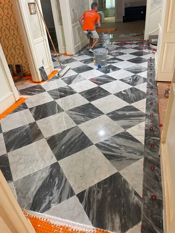A man is cleaning a checkered marble floor with a mop.