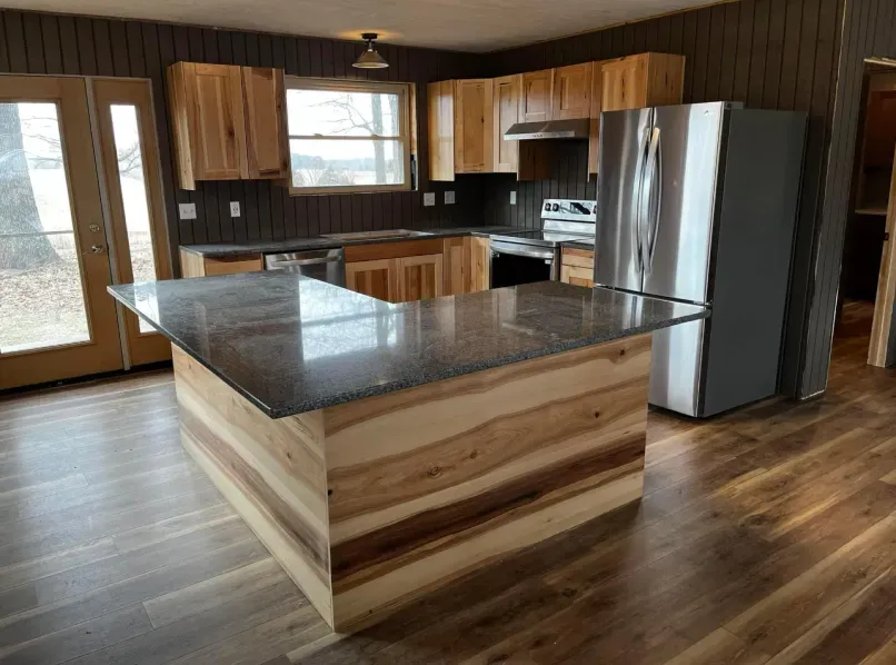 A kitchen with wooden cabinets , granite counter tops , stainless steel appliances and a large island.