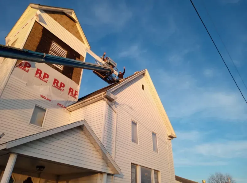 A man is painting the side of a building with a crane.