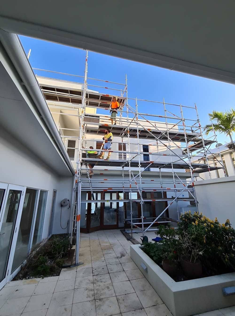A Man is Standing on a Scaffolding on the Side of a Building — All Coast Scaffolding In Yandina, QLD