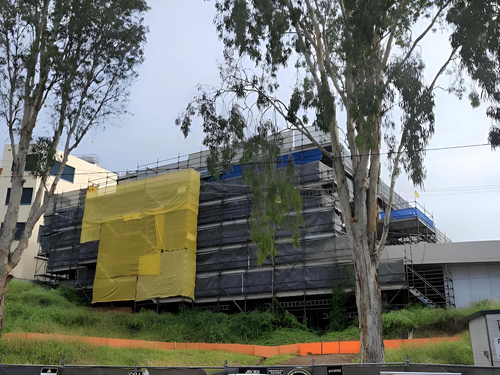 A Building Under Construction With a Yellow Tarp Covering It — All Coast Scaffolding In Yandina, QLD