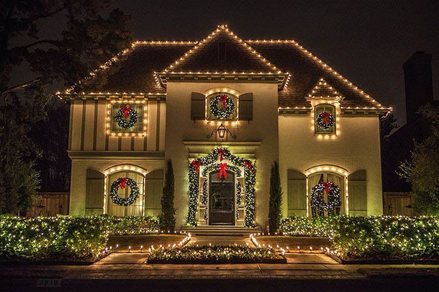 House decorated with Christmas lights and wreaths, illuminated at night.