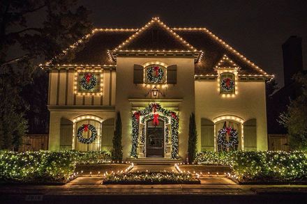 House decorated with Christmas lights and wreaths, illuminated at night.