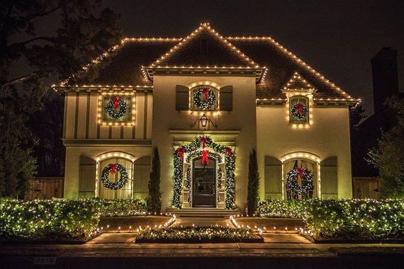 House decorated with Christmas lights and wreaths, illuminated at night.