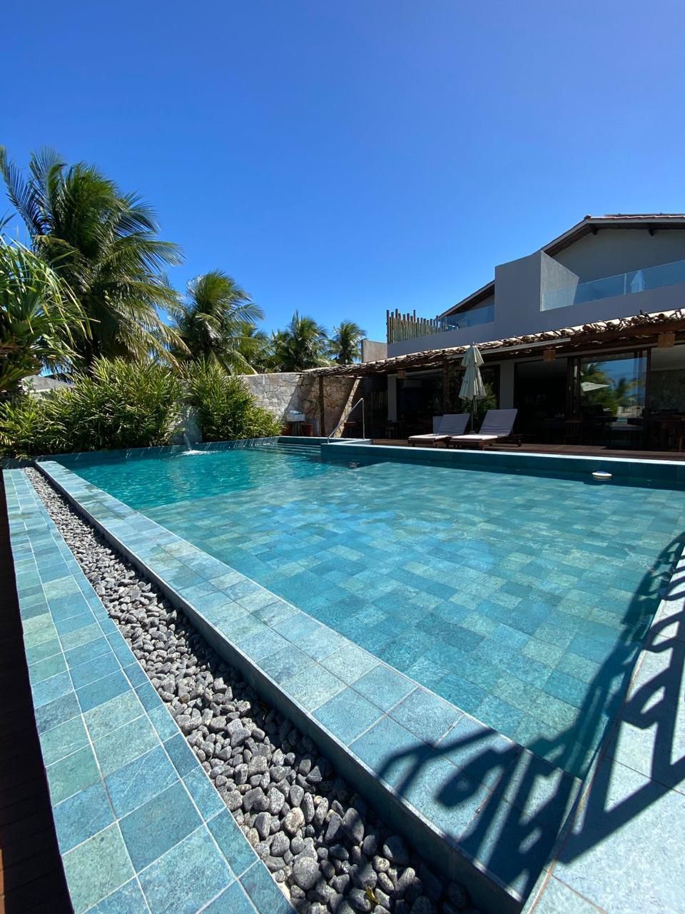 Piscina com azulejos turquesa e pedras escuras, ao lado de uma casa em um dia ensolarado.Pousada Villa Italiana