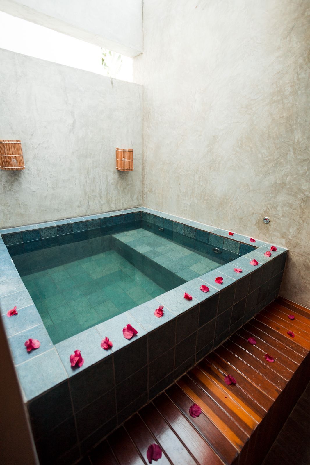 Spa interno com banheira de azulejos e piso de madeira, decorado com pétalas de rosa.Pousada Villa Italiana