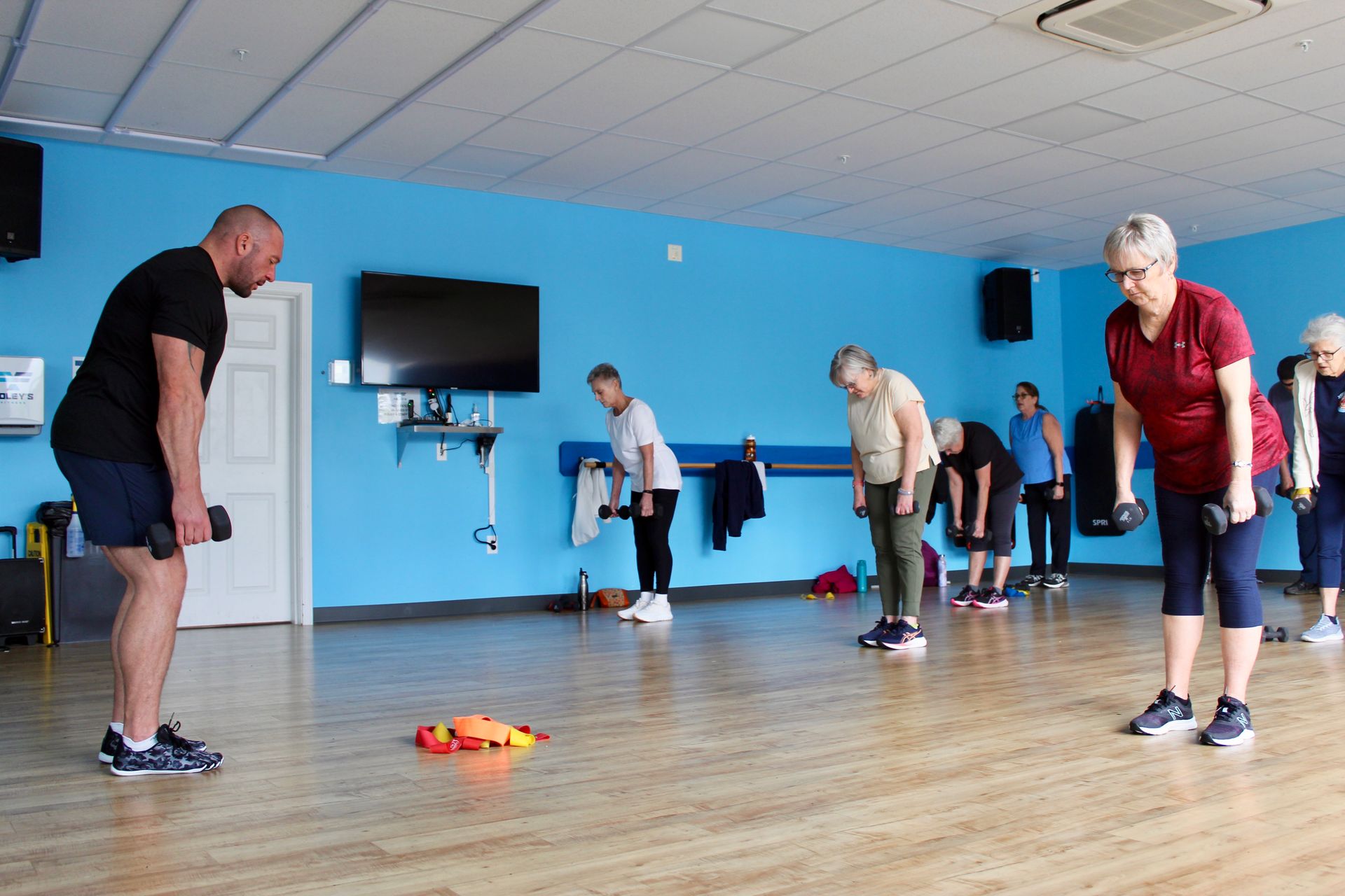 People exercising with dumbbells in a blue-walled gym.
