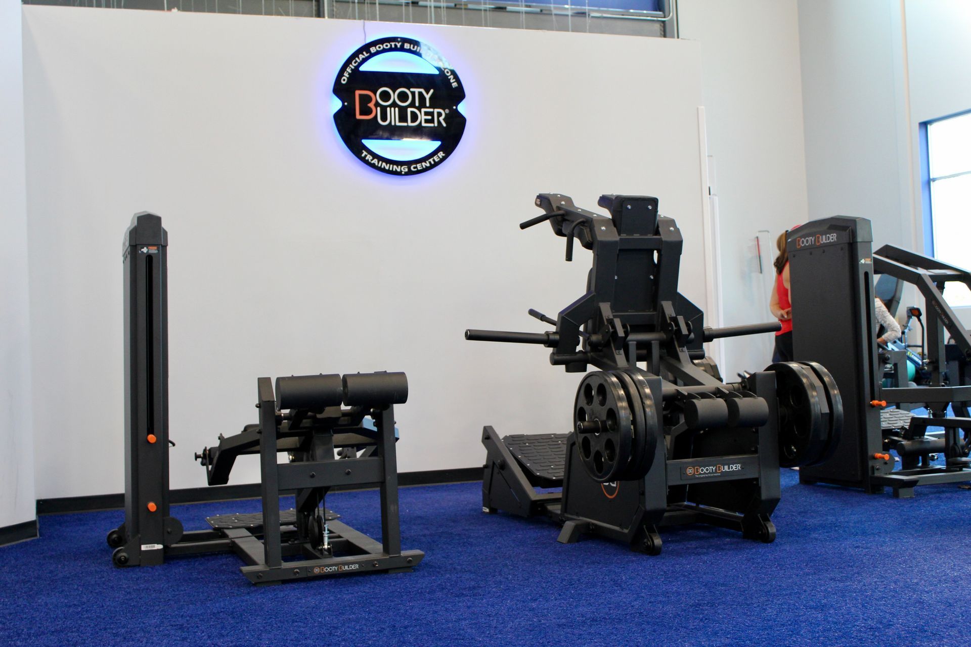 A gym interior with dark exercise machines on a blue floor, and a 
