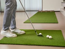 Golfer preparing to putt on indoor green turf, with two golf balls nearby