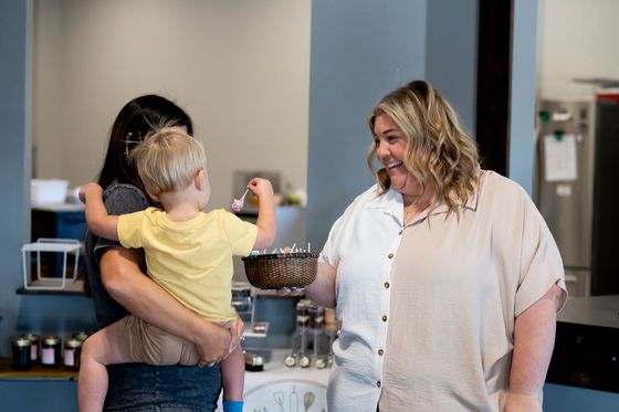 A woman is holding a baby and a woman is holding a cake.