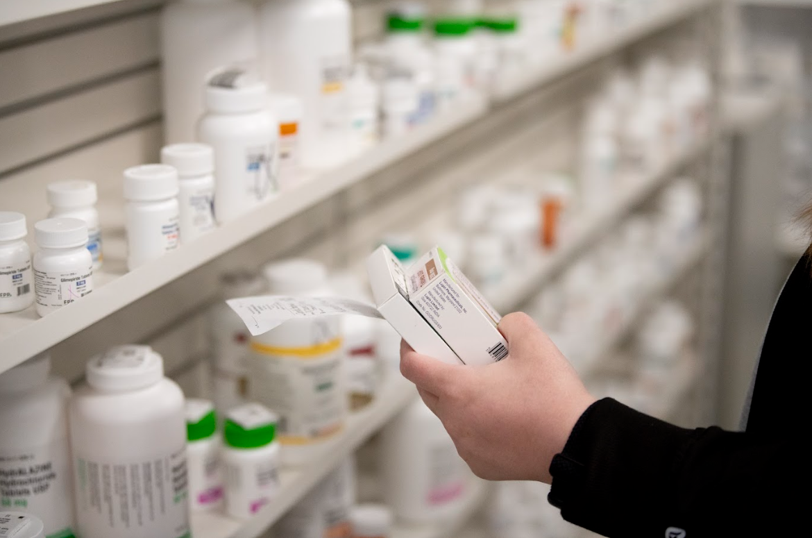 A person is looking at a box of pills in a pharmacy.