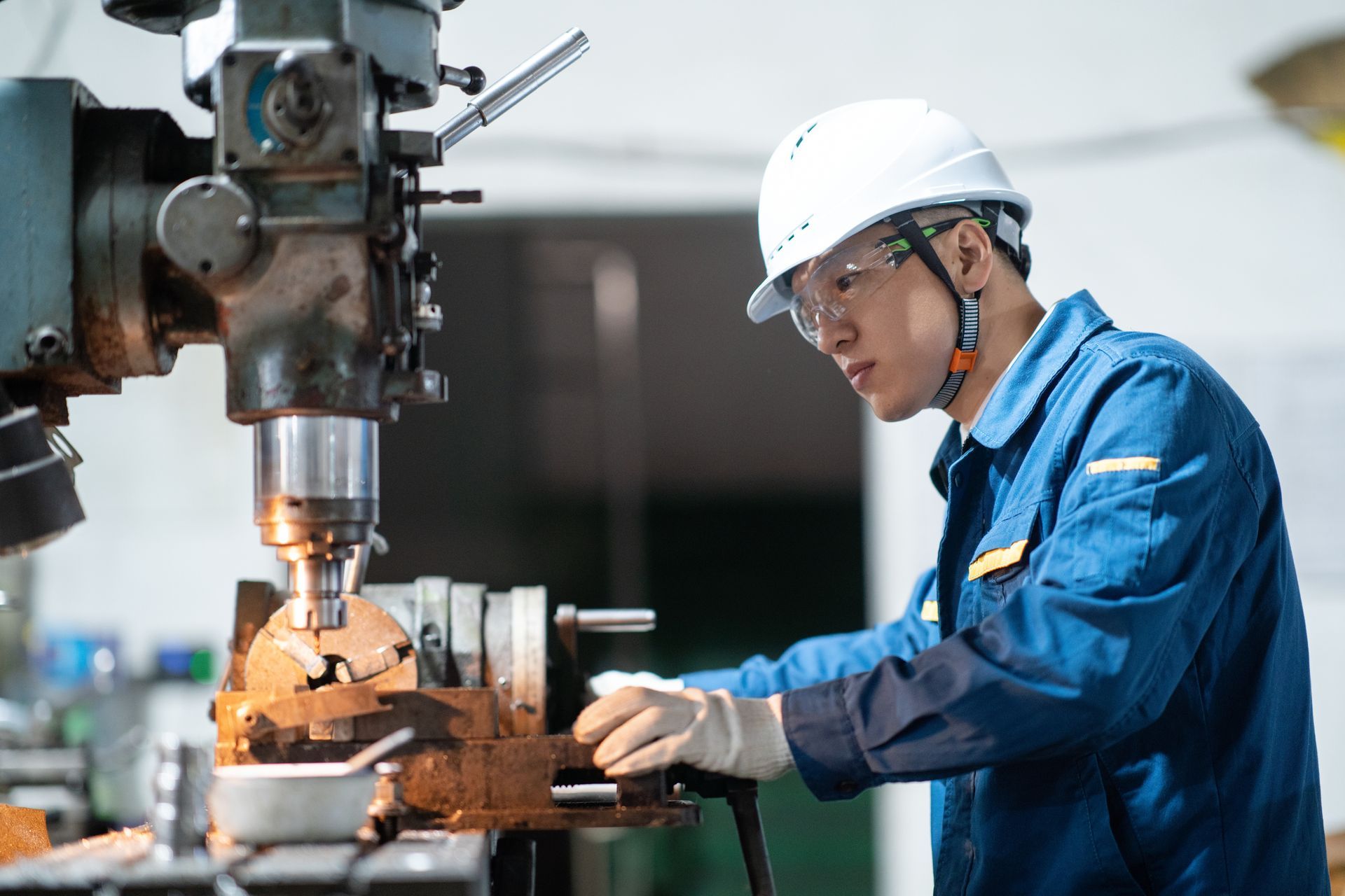 Technician operating a lathe machine to shape custom metal parts.