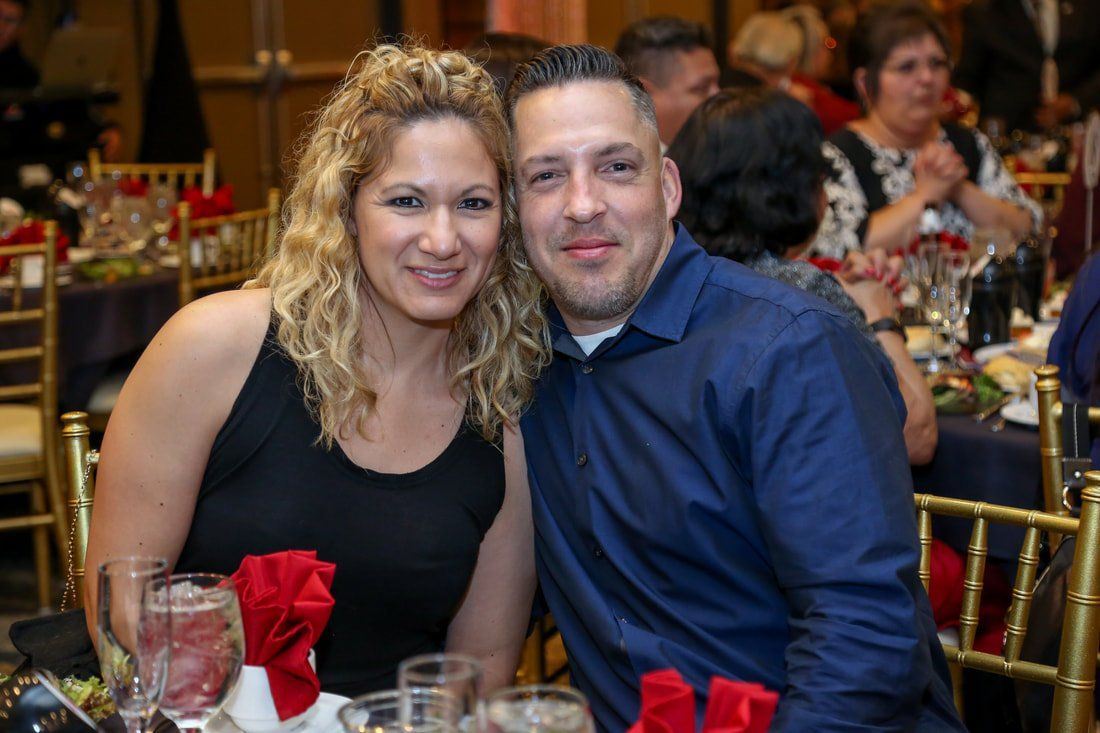 A man and a woman are posing for a picture at a dinner table.