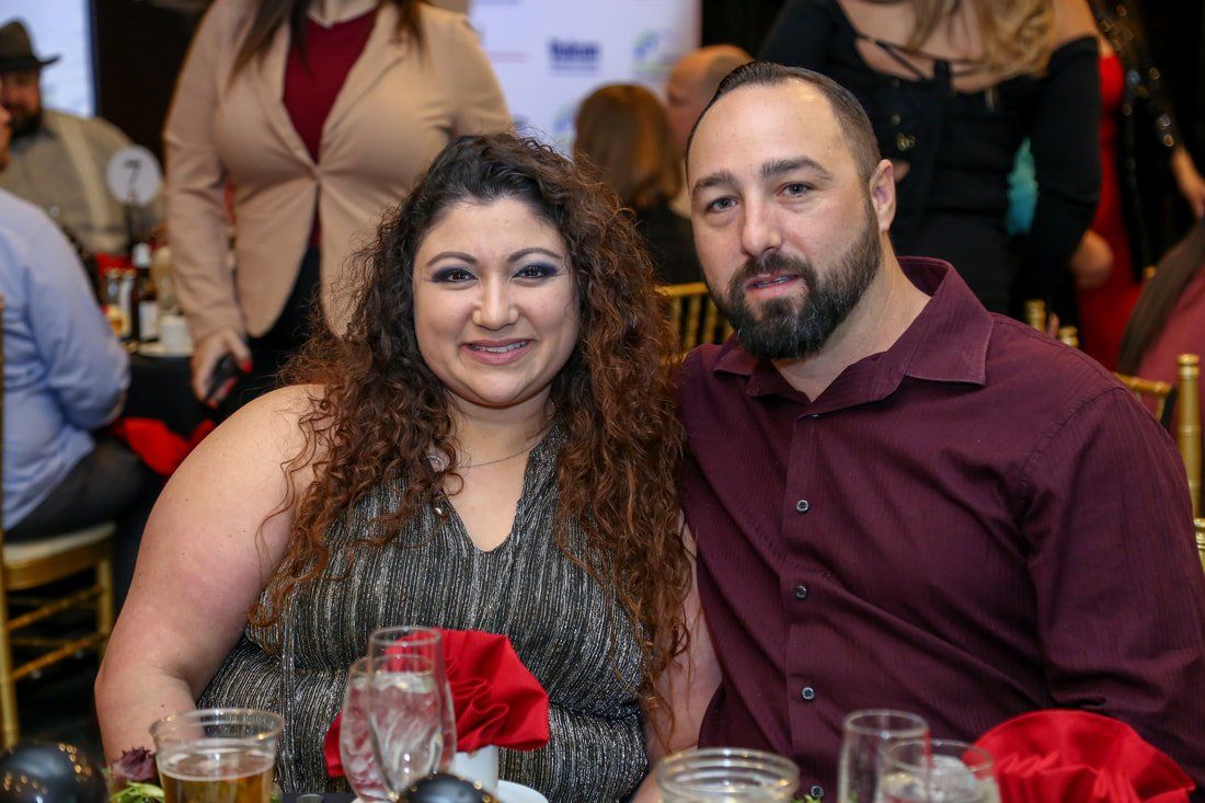 A man and a woman are sitting at a table at a party.