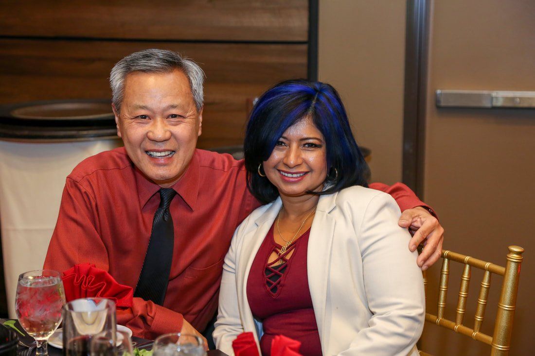 A man and a woman are posing for a picture at a table.