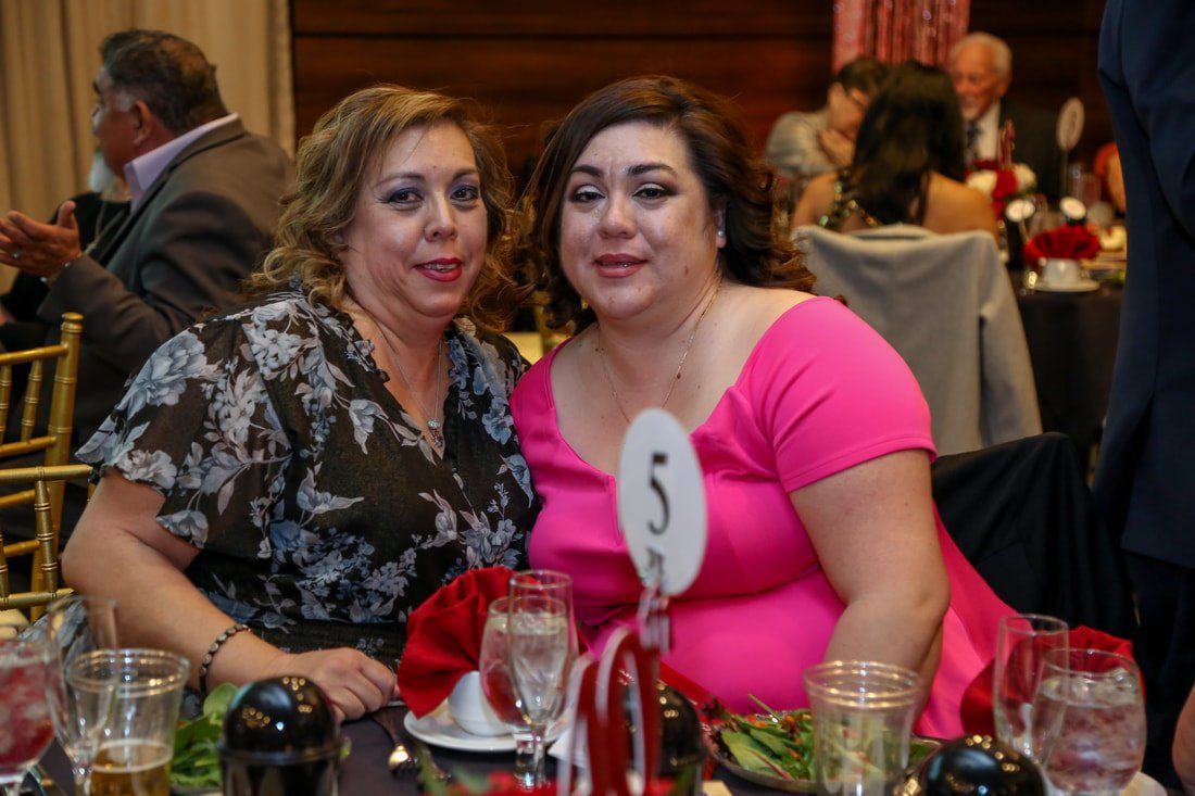 Two women are sitting at a table with a number 5 on it.