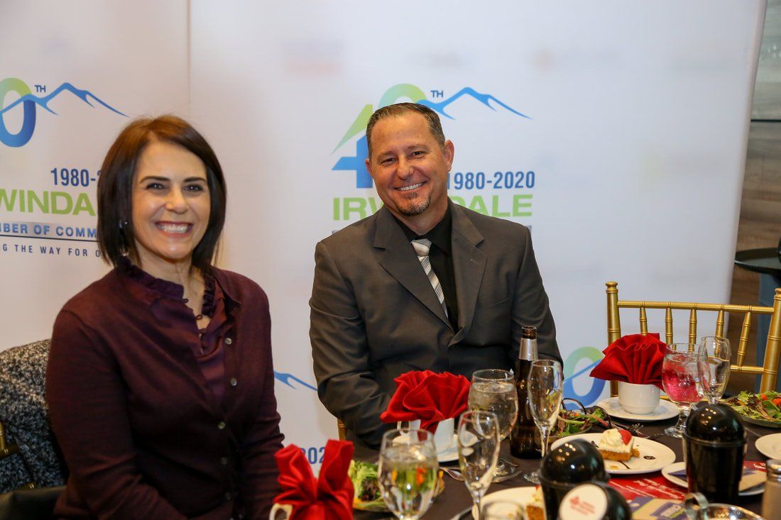 A man and a woman are sitting at a table with wine glasses.