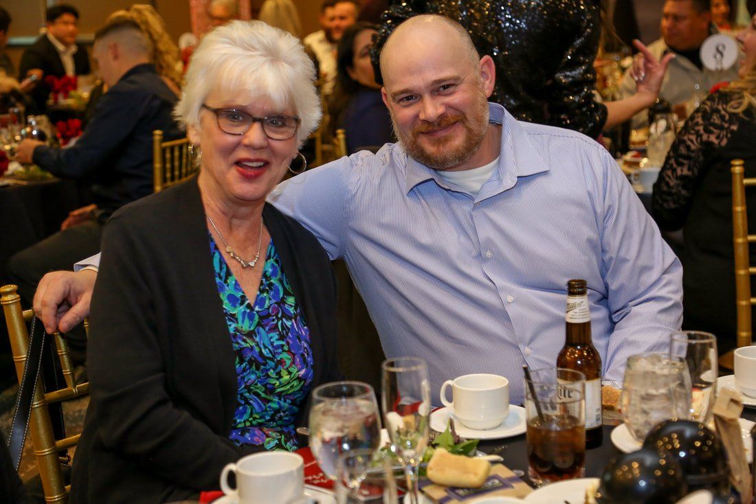 A man and a woman are posing for a picture at a dinner table.