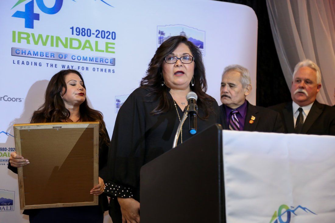 A woman is standing at a podium holding a framed picture.