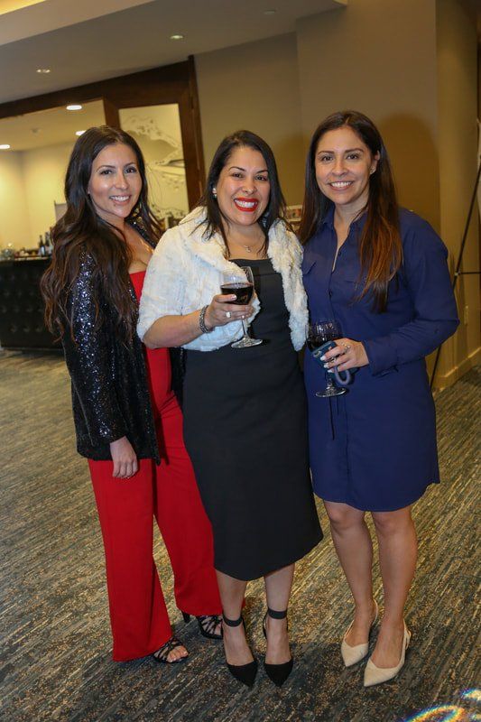 Three women are posing for a picture together while holding wine glasses.