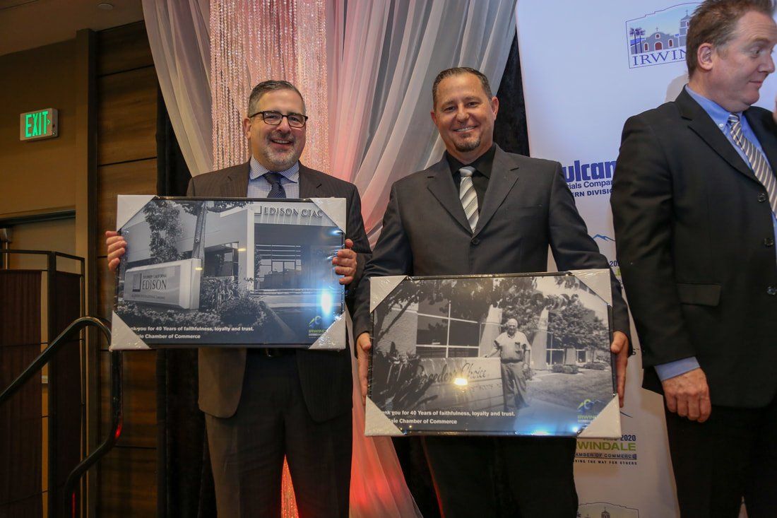Two men in suits and ties are holding framed pictures