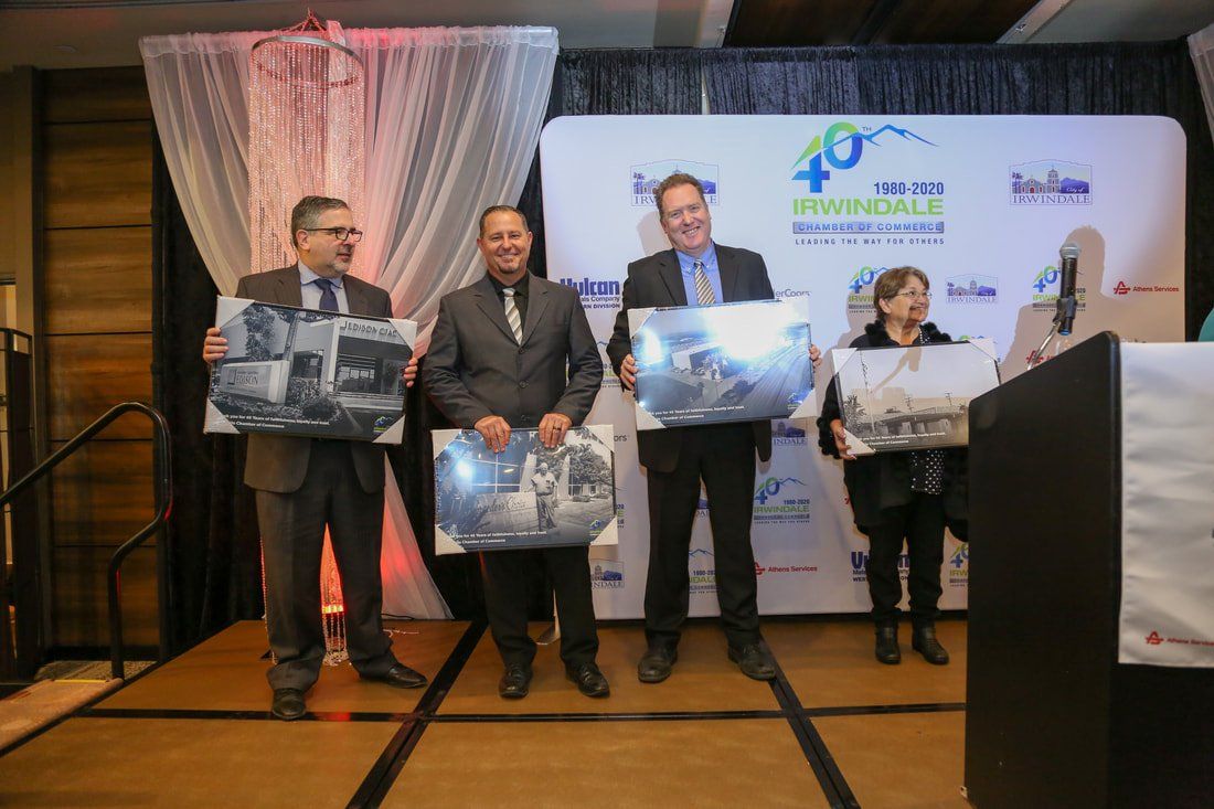 A group of people are standing on a stage holding pictures.