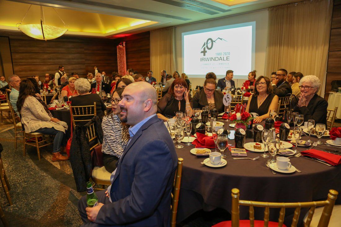 A man in a suit is sitting at a table at a dinner party.